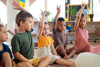 Children raising hands indoors